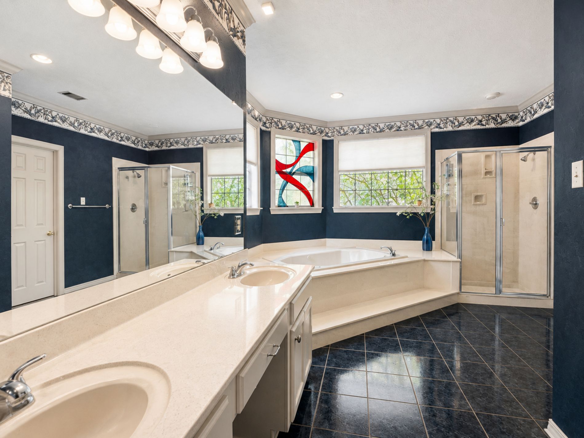 Primary bathroom with double sinks, soaking tub, shower, and large walk-in closet